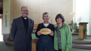 Parishioners and parish priest showing award plaque