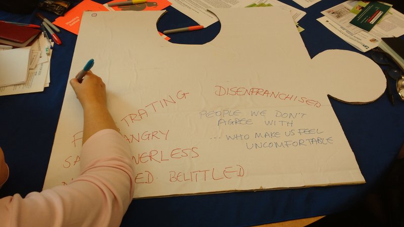 people writing on blank side of giant jigsaw piece