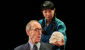 A man with a skull with a Japanese woman looking on