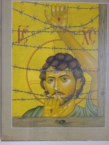 The image of Christ with barbed wire is known as the 'Maryknoll Christ'. It is deliberately ambiguous. Is Jesus imprisoned behind the barbed wire - or is he looking at us through barbed wire?